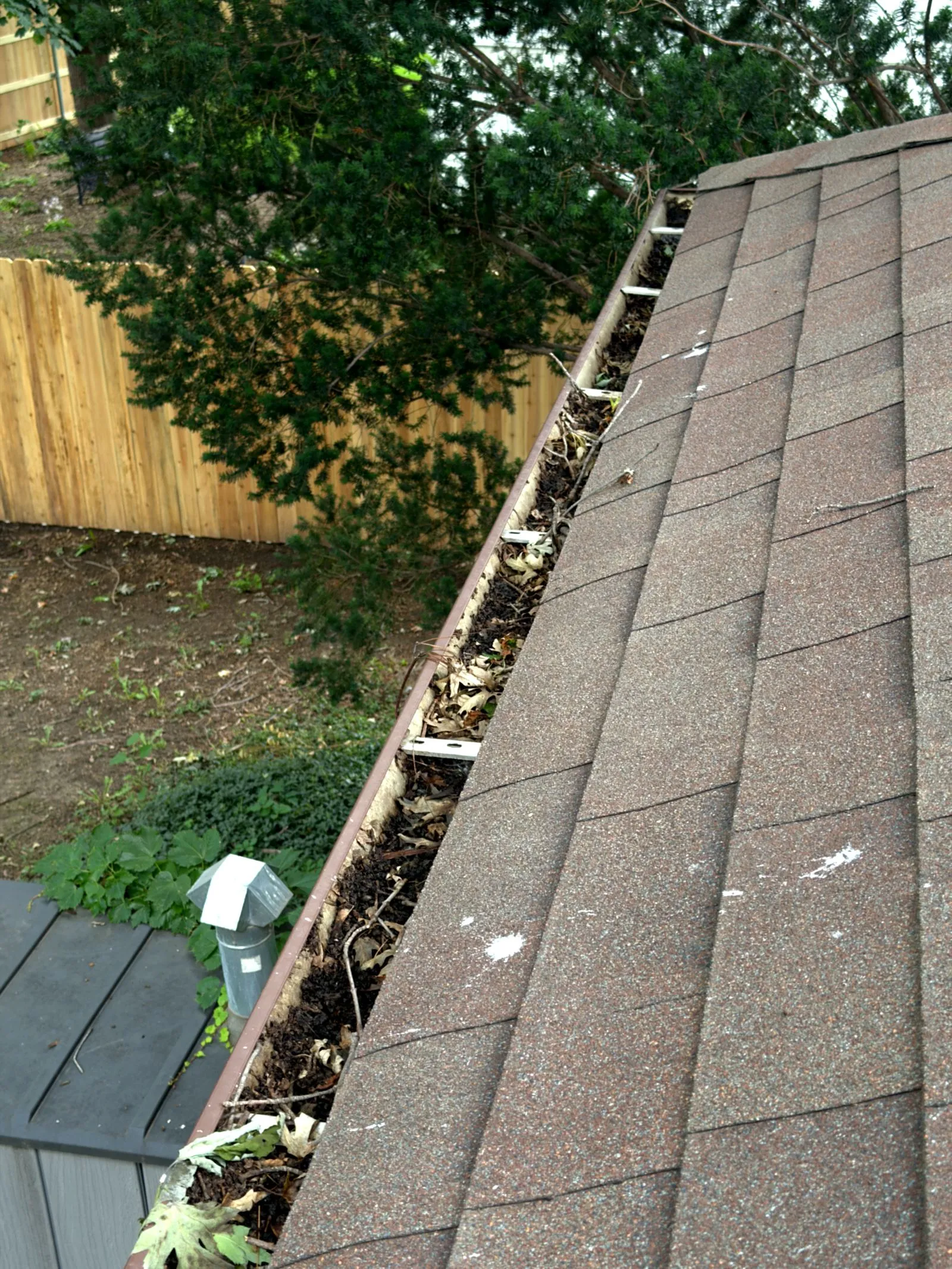 Gutter packed with leaves, sticks, and sludge before cleaning at a Lincoln, NE home