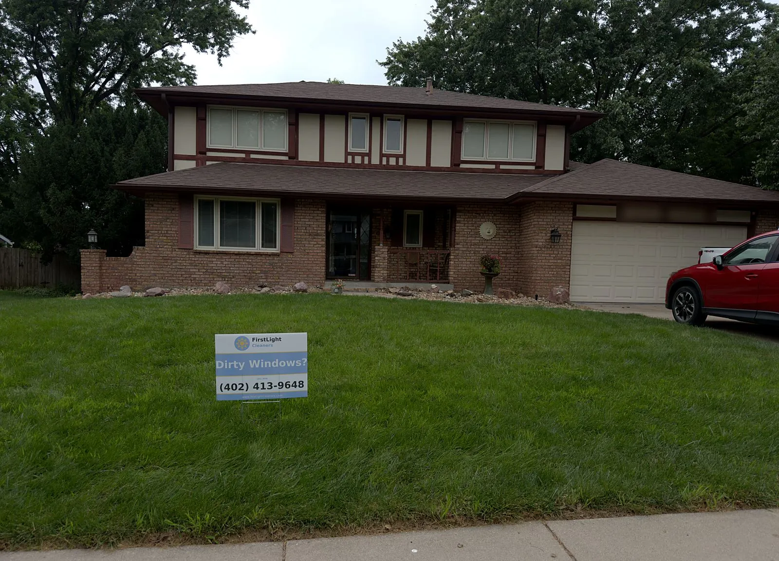 First Light Cleaners yard sign in the front lawn of a completed two-story window cleaning job in Lincoln, NE