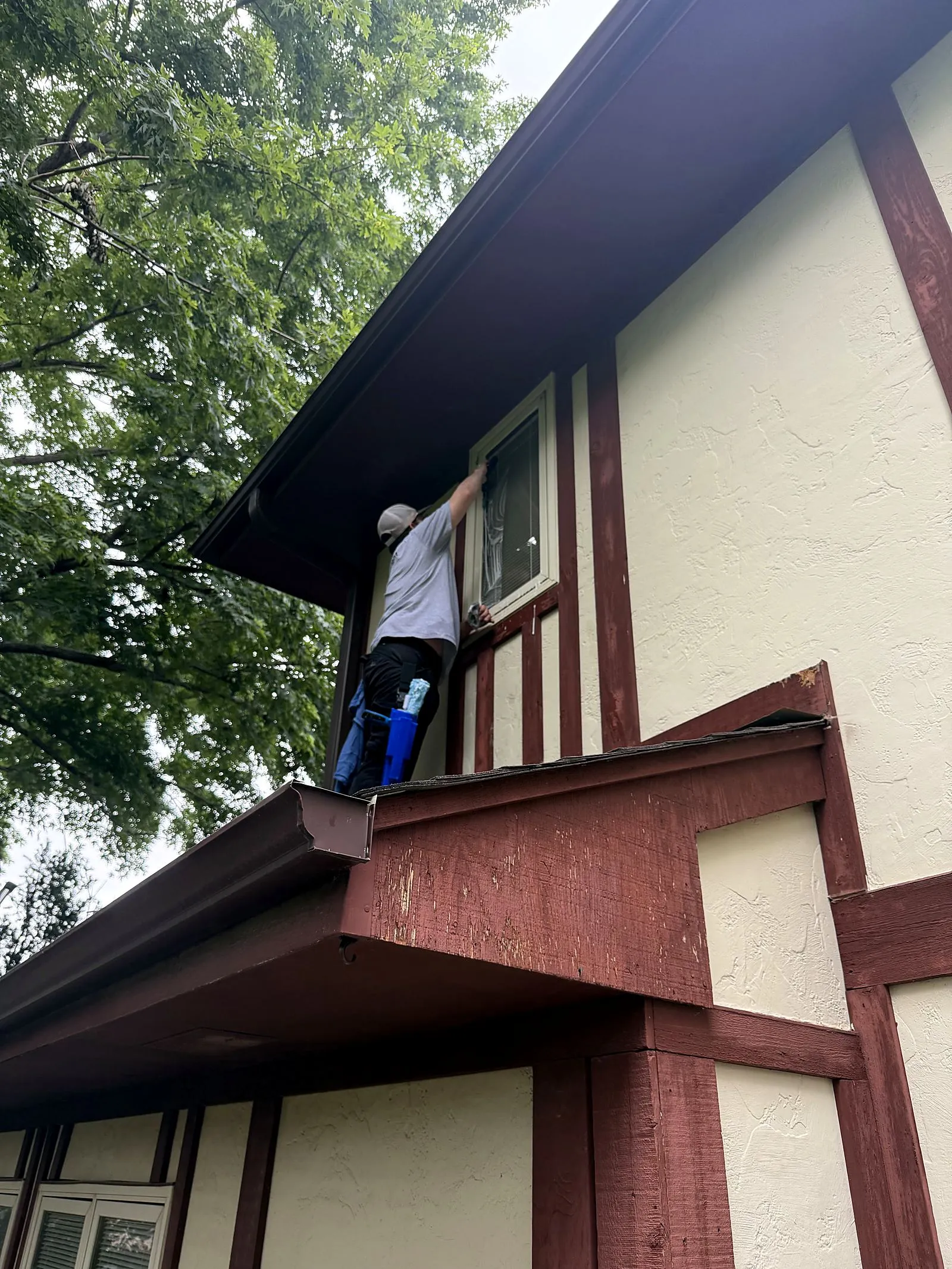 First Light Cleaners technician hand-detailing an upper window of a Lincoln home